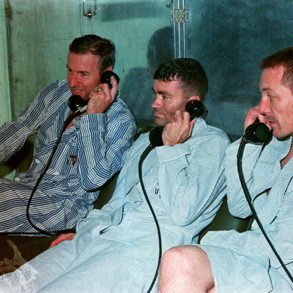 Jim Lovell (left), Fred Haise, and Jack Swigert receive a phone call on board the Iwo Jima. The fact that it is a group call and that a photo was taken suggest that the call is from President Nixon. 17 April 1970. Scan by J.L. Pickering.